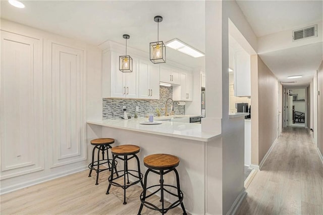 502 Brighton Pt, Atlanta, GA 30328 - kitchen featuring light wood finished floors, white cabinets, a peninsula, and a breakfast bar area