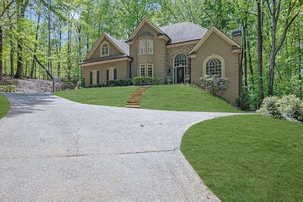 view of front facade with a front lawn, stone siding, and stucco siding