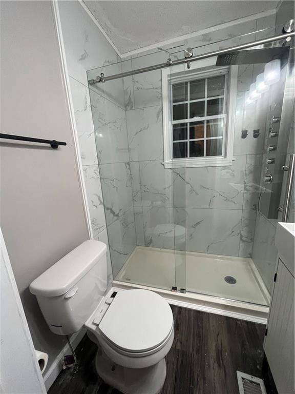 bathroom with wood-type flooring, vanity, toilet, and a shower with shower door