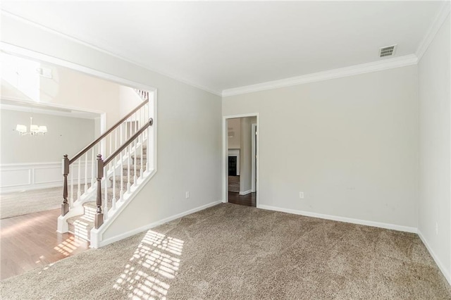 carpeted spare room with stairs, ornamental molding, visible vents, and an inviting chandelier