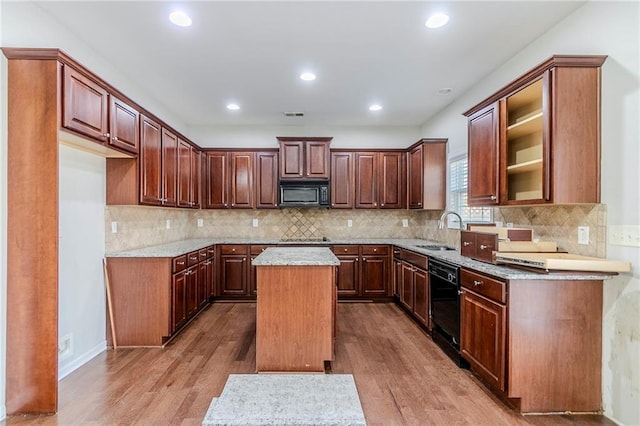 kitchen with black appliances, a kitchen island, a sink, and wood finished floors