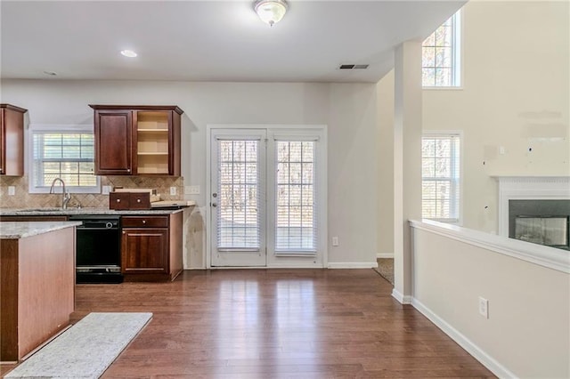 kitchen featuring dark wood-style flooring, a sink, visible vents, black dishwasher, and tasteful backsplash