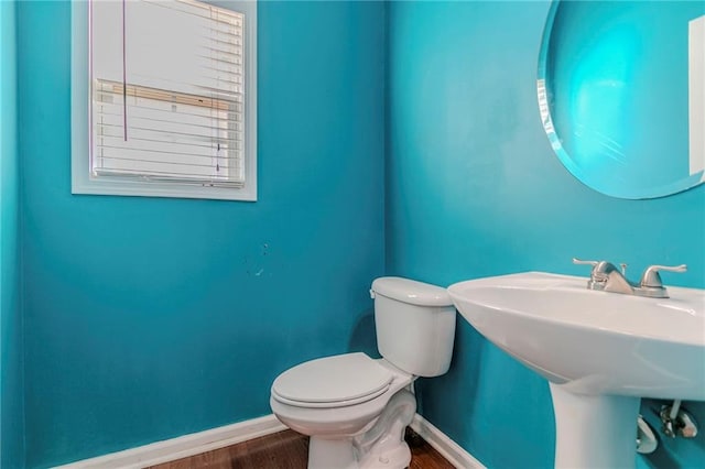 bathroom with a sink, wood finished floors, toilet, and baseboards