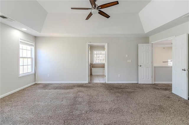 spare room featuring carpet floors, a tray ceiling, plenty of natural light, and visible vents