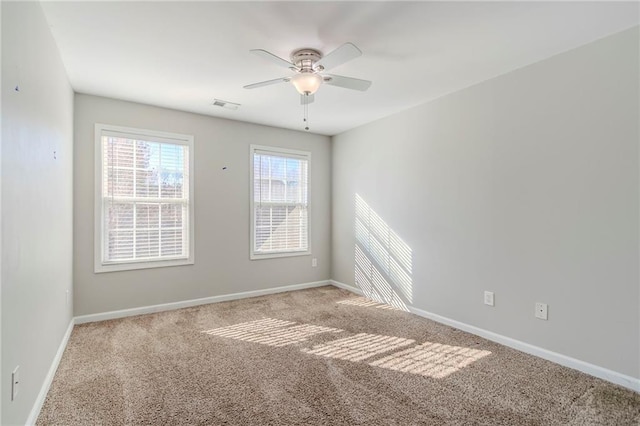 empty room featuring carpet floors, a ceiling fan, visible vents, and baseboards