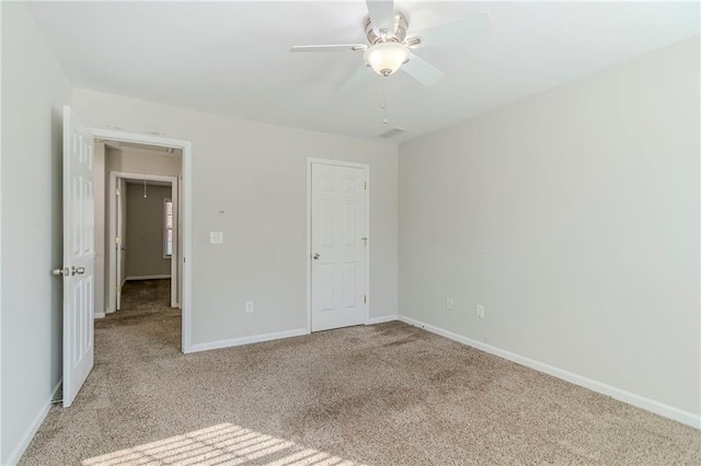 unfurnished bedroom with attic access, ceiling fan, carpet floors, and baseboards