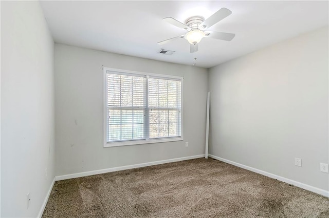 carpeted spare room featuring a ceiling fan, visible vents, and baseboards