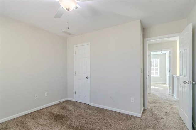 unfurnished bedroom with attic access, light colored carpet, and baseboards