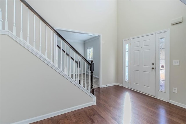 foyer entrance with stairs, crown molding, wood finished floors, and baseboards