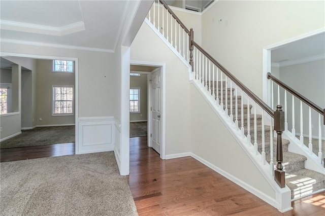 stairs featuring ornamental molding, wainscoting, and wood finished floors