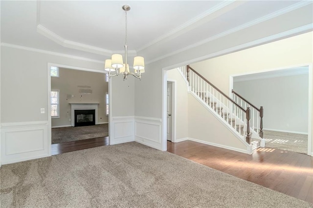 unfurnished room featuring wainscoting, stairway, wood finished floors, crown molding, and carpet flooring