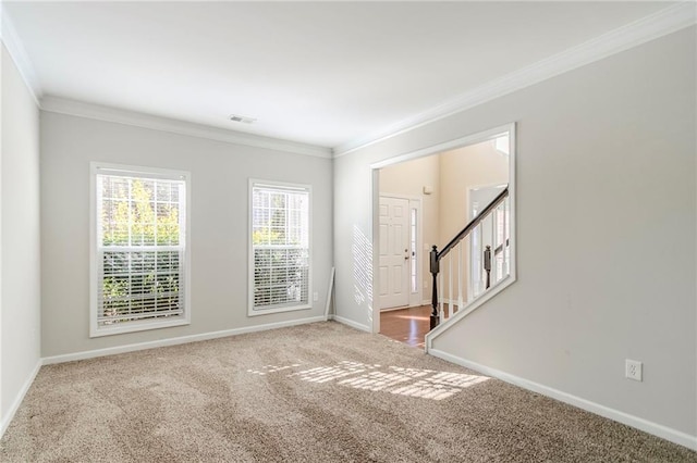 carpeted spare room featuring stairs, baseboards, visible vents, and crown molding