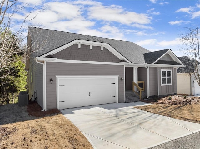 view of front of home with concrete driveway, central AC, an attached garage, and roof with shingles