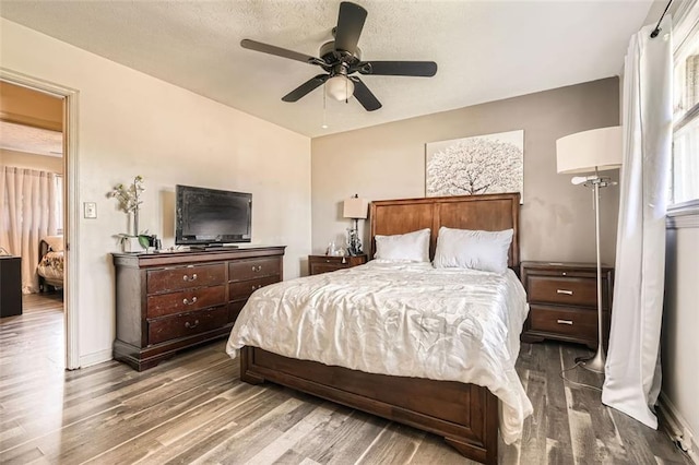 bedroom with a textured ceiling, hardwood / wood-style flooring, and ceiling fan