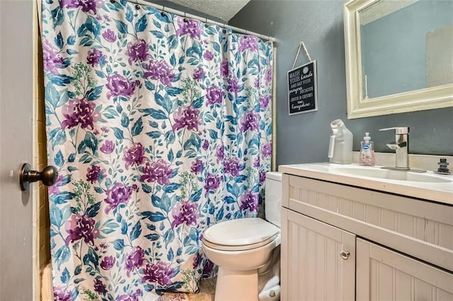 bathroom with walk in shower, vanity, a textured ceiling, and toilet