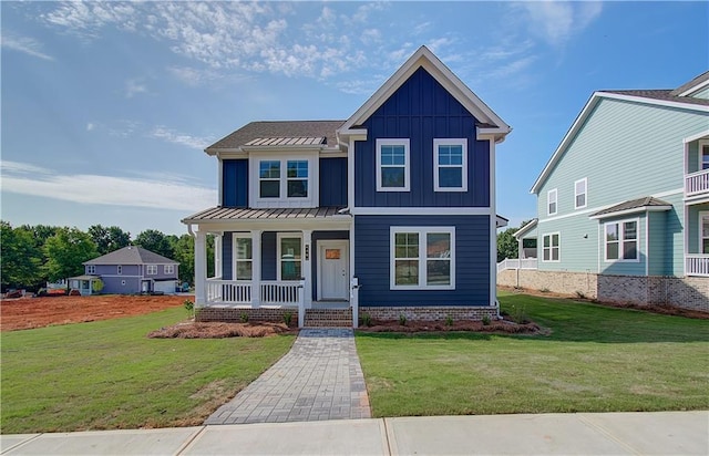 view of front of house featuring covered porch, board and batten siding, a front yard, and a standing seam roof