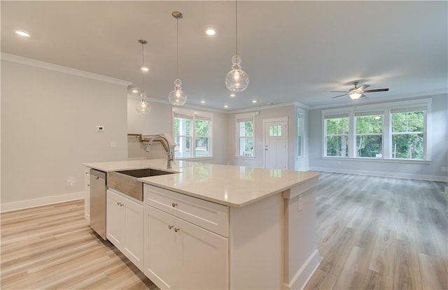 kitchen with light wood-style flooring, a kitchen island with sink, a sink, open floor plan, and dishwasher