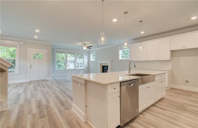 kitchen with a warm lit fireplace, a sink, stainless steel dishwasher, crown molding, and open floor plan