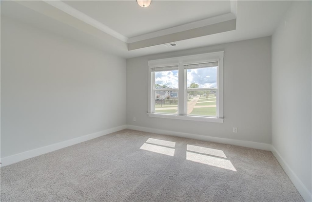 unfurnished room featuring light colored carpet, a tray ceiling, baseboards, and visible vents