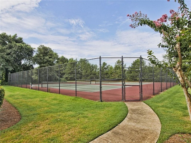 view of tennis court with a gate, a yard, and fence