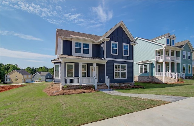 view of front facade with a standing seam roof, a front lawn, covered porch, and board and batten siding