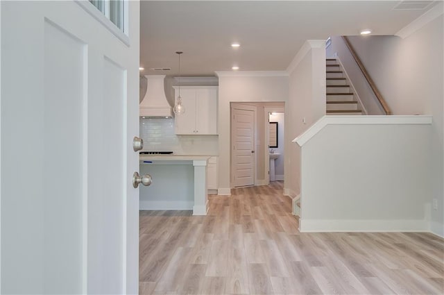 kitchen featuring premium range hood, light countertops, decorative backsplash, light wood-style floors, and white cabinets