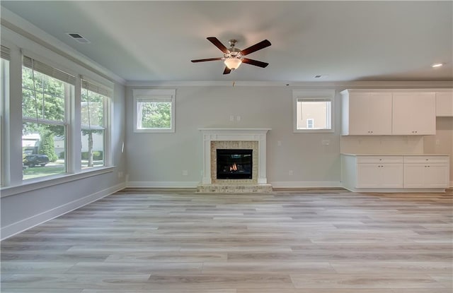 unfurnished living room with a glass covered fireplace, visible vents, light wood-type flooring, and baseboards