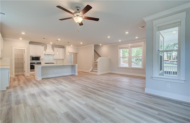 unfurnished living room featuring visible vents, crown molding, baseboards, light wood-type flooring, and stairs