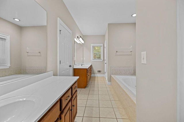 bathroom featuring tile patterned flooring, vanity, and tiled bath