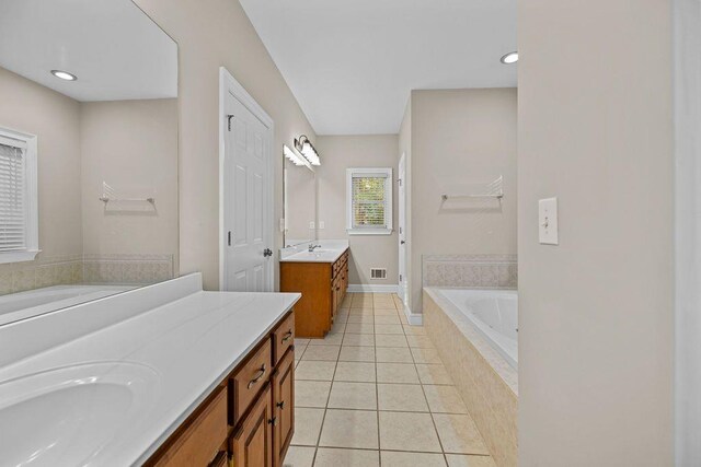 bathroom with tile patterned flooring, vanity, and tiled tub