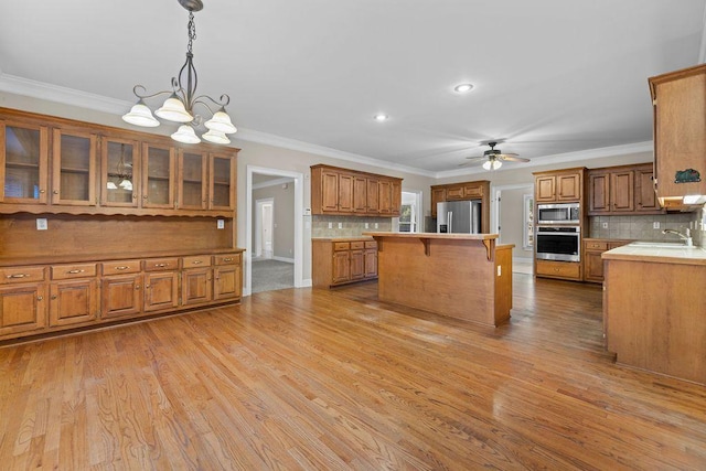 kitchen featuring a breakfast bar, tasteful backsplash, decorative light fixtures, a center island, and appliances with stainless steel finishes