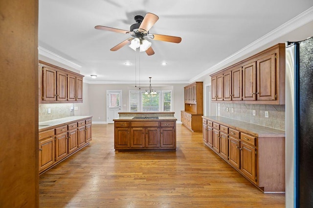 kitchen with ornamental molding, light hardwood / wood-style flooring, black electric stovetop, and decorative light fixtures