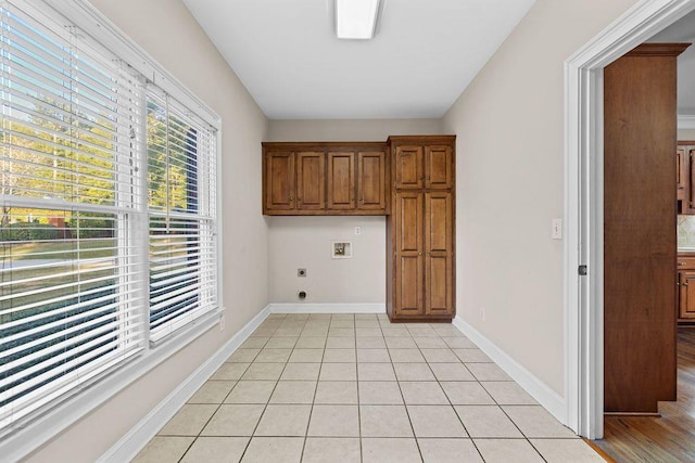 laundry room with electric dryer hookup, washer hookup, light tile patterned floors, and cabinets