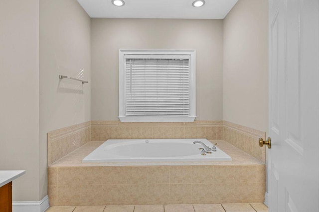 bathroom featuring a relaxing tiled tub, vanity, and tile patterned flooring