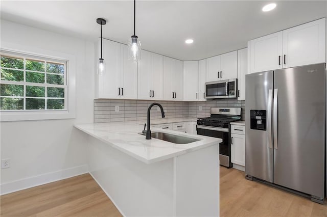 1409 Georgia Ave, East Point, GA 30344 - kitchen featuring appliances with stainless steel finishes, a peninsula, light wood finished floors, light stone counters, and recessed lighting