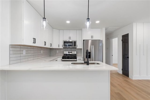 1409 Georgia Ave, East Point, GA 30344 - kitchen featuring appliances with stainless steel finishes, light stone counters, a peninsula, tasteful backsplash, and recessed lighting