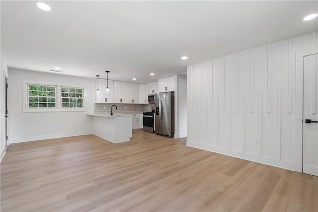 1409 Georgia Ave, East Point, GA 30344 - kitchen with appliances with stainless steel finishes, light countertops, a peninsula, open floor plan, and light wood-style floors