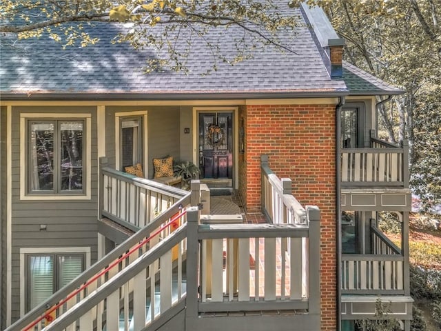 470 Ansley Walk Ter NE, Atlanta, GA 30309 - property entrance with roof with shingles, brick siding, covered porch, and a chimney