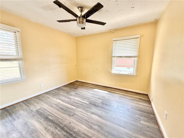 unfurnished room with plenty of natural light, a textured ceiling, and wood finished floors