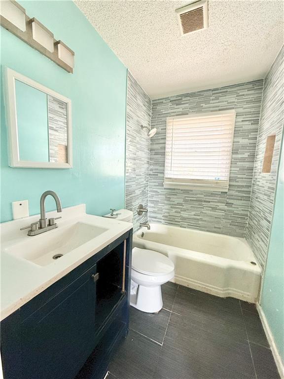 bathroom featuring vanity, visible vents, a textured ceiling, shower / bathing tub combination, and toilet