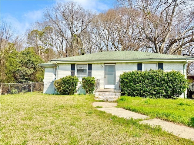 ranch-style home with a front yard, fence, and brick siding