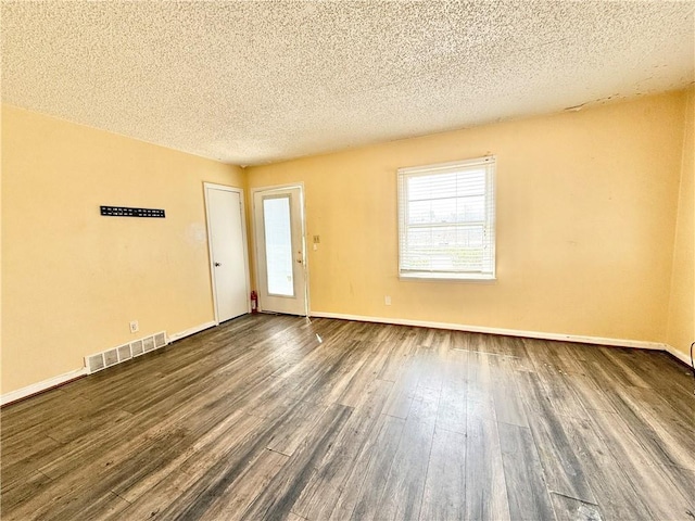 unfurnished room with visible vents, a textured ceiling, dark wood-type flooring, and baseboards