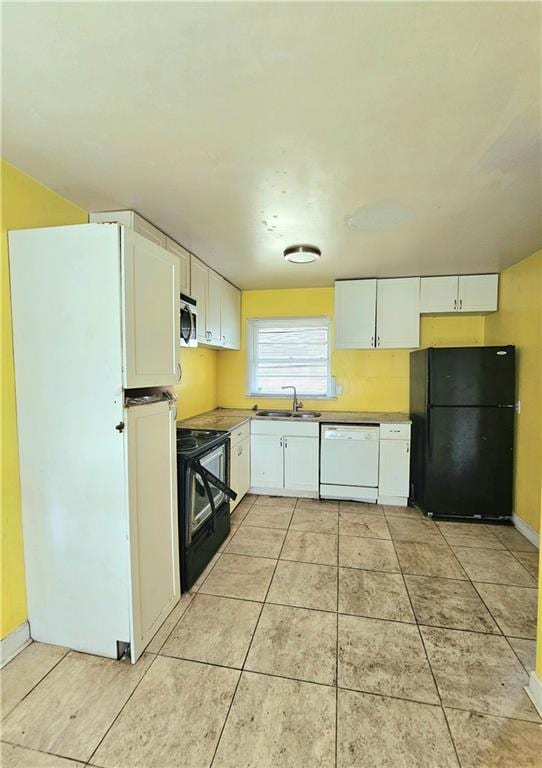 kitchen featuring freestanding refrigerator, a sink, range with electric stovetop, dishwasher, and stainless steel microwave