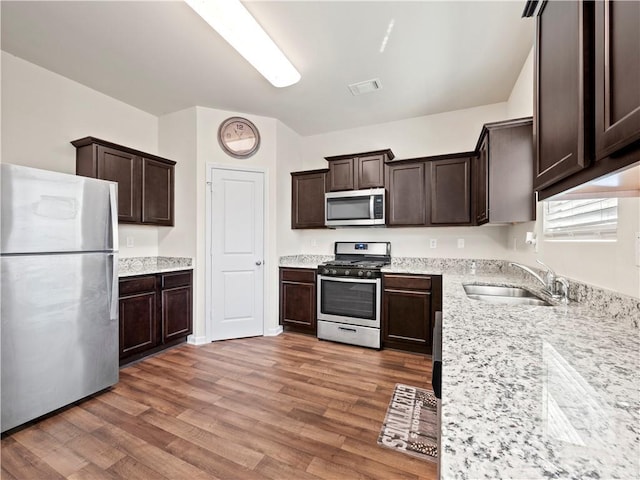 kitchen with appliances with stainless steel finishes, visible vents, a sink, and dark brown cabinets