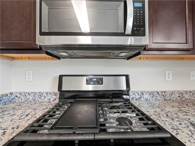 kitchen featuring dark brown cabinets, appliances with stainless steel finishes, and light stone countertops