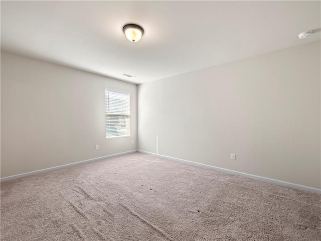 spare room featuring carpet floors, visible vents, and baseboards