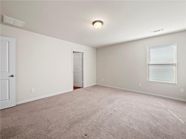 carpeted spare room with visible vents and baseboards