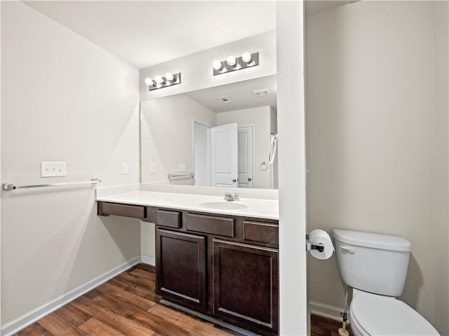 bathroom featuring vanity, wood finished floors, toilet, and baseboards