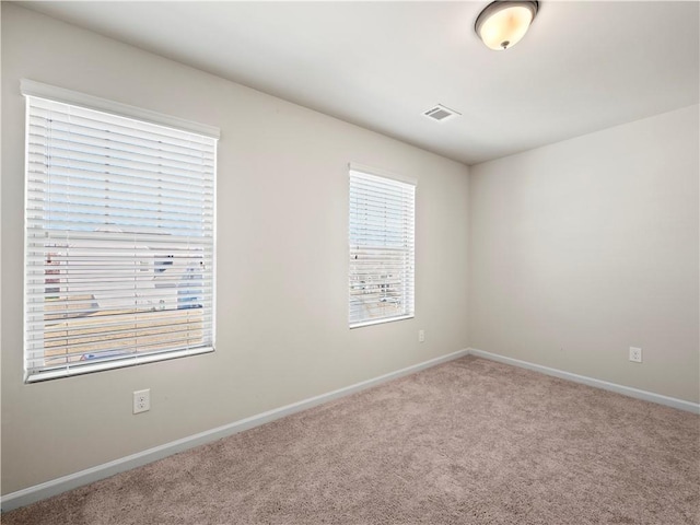 unfurnished room featuring carpet, visible vents, and baseboards