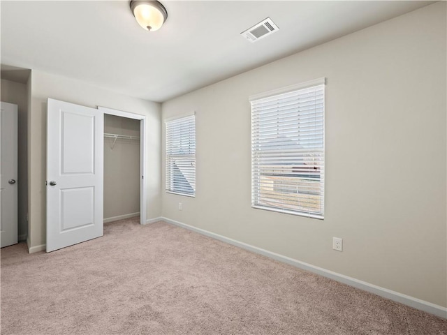 unfurnished bedroom with light colored carpet, a closet, visible vents, and baseboards